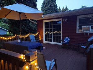 A wooden deck with a table and chairs, string lights, and a large umbrella. - Charming 3 Bedroom Home with Spacious Deck & Boat Parking, near Elk Creek (GIRARD)