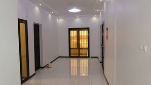 A hallway with white walls, a tiled floor, and a door with a golden gate.