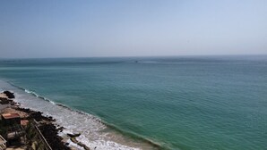 A coastal view with a clear sky, calm sea, and rocky shoreline.
