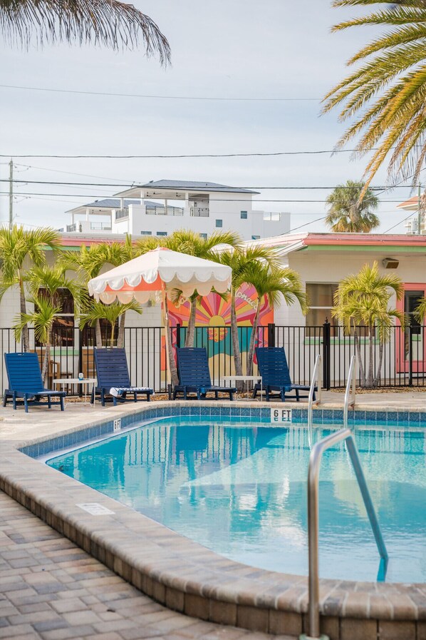 A swimming pool with lounge chairs and a colorful mural in the background. - Peach Paradise Two Bedroom Apartment Steps From The Beach (Clearwater)