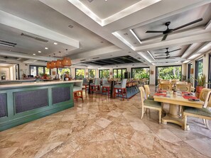 Enjoy a comfortable dining experience in this well-appointed space with high ceilings, polished tiles, and large windows offering views of the surrounding greenery.