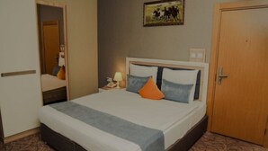 Ein ordentlich eingerichtetes Schlafzimmer mit einem Bett, einem Nachttisch, einer Lampe und einer Tür.