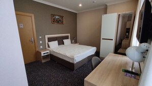 Ein Hotelzimmer mit Bett, Nachttisch, Schreibtisch, Stuhl und Fernseher.