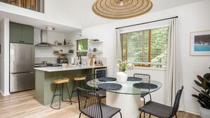 Una cocina moderna con una isla central, taburetes de bar y una mesa de comedor con sillas.