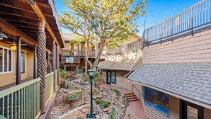 A courtyard with a stone pathway, a tree, and a building with a balcony. - Lovely 1 Bedroom Flat in Downtown Estes Lic#6074 (Estes Park)