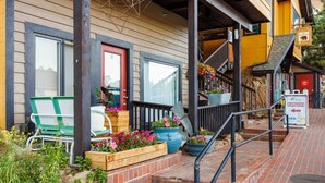 A building with a porch, outdoor seating, and flower planters. - Lovely 1 Bedroom Flat in Downtown Estes Lic#6074 (Estes Park)