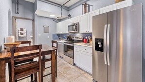 A modern kitchen with white cabinets, stainless steel appliances, and a wooden dining table. - Lovely 1 Bedroom Flat in Downtown Estes Lic#6074 (Estes Park)