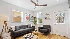A modern living room with a grey sofa, a round wooden coffee table, and a ceiling fan.
