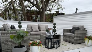 An outdoor patio area with wicker furniture, potted plants, and a small table.