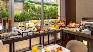 A breakfast buffet with various food items and beverages, a view of greenery outside, and a modern interior design. - Hotel Cabrera Imperial By Key 33 (Bogotá)