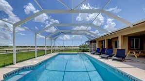 A covered swimming pool with lounge chairs and a view of the countryside. - 1.2 MILE MOTOCROSS TRACK / 4-BED, 3-BA, HEATED POOL HOME  (Fort Pierce)