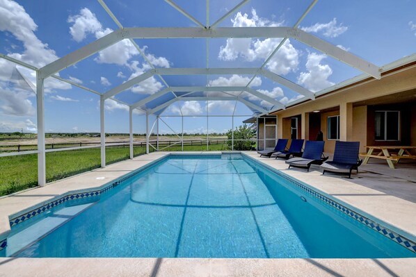 A covered swimming pool with lounge chairs and a view of the countryside. - 1.2 MILE MOTOCROSS TRACK / 4-BED, 3-BA, HEATED POOL HOME (Fort Pierce)