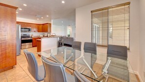 A modern kitchen with stainless steel appliances, a dining area with a glass table and chairs, and a large window with blinds. - 1.2 MILE MOTOCROSS TRACK / 4-BED, 3-BA, HEATED POOL HOME  (Fort Pierce)