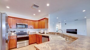 A modern kitchen with wooden cabinets, stainless steel appliances, granite countertops, and a built-in dishwasher. - 1.2 MILE MOTOCROSS TRACK / 4-BED, 3-BA, HEATED POOL HOME  (Fort Pierce)