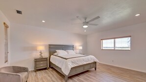 A bedroom with a bed, nightstands, a chair, a ceiling fan, and a window. - 1.2 MILE MOTOCROSS TRACK / 4-BED, 3-BA, HEATED POOL HOME  (Fort Pierce)