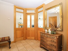 Una habitación de esquina con puertas de madera, un banco, un aparador y un espejo.