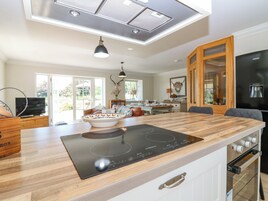 Una cocina moderna con una isla grande, horno empotrado y un comedor con vistas al exterior.