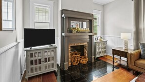 Una sala de estar con chimenea, televisor y sofá.