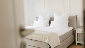 A bedroom with a bed, pillows, a nightstand, and a lamp.