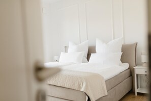 A bedroom with a bed, pillows, a nightstand, and a lamp.