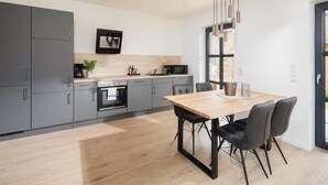 A modern kitchen with grey cabinets, a wooden dining table, and black chairs.
