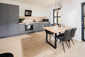 Una cocina moderna con armarios grises, una mesa de comedor de madera y sillas negras.