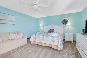Un dormitorio con cama, mesita de noche, cómoda, ventilador de techo y lámpara de pared.