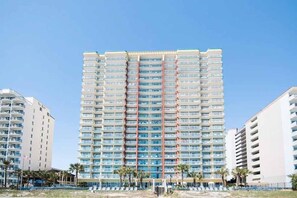 Ein Hochhaus-Hotel mit zahlreichen Balkonen, einem zentralen Atrium und einer Strandlage.