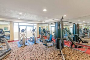 A gym with various exercise equipment, large windows, and a patterned carpet. - Oceanfront Myrtle Beach Condo: Beach Views & Pool! (Myrtle Beach)