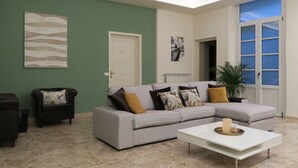 Ein modernes Wohnzimmer mit einem grauen Ecksofa, einem weißen Couchtisch und einer grünen Akzentwand.