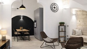 A modern interior with a dining area, two chairs, a sofa, a clock, and a bookshelf.