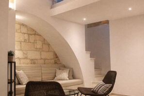 A cozy seating area with a stone wall, a sofa, and two chairs. - Giorì House (Nardò)