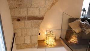 A staircase with a stone wall, a glass railing, and a light fixture.