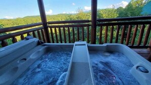 Ein Whirlpool auf einer Holzterrasse mit Blick auf eine bewaldete Landschaft.