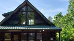A log cabin with a triangular roof and large windows.