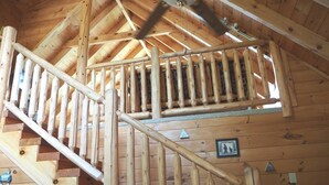 A wooden staircase with a ceiling fan in a log cabin interior.