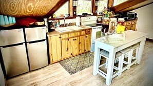 A kitchen with wooden cabinets, a white countertop, and a dining table.