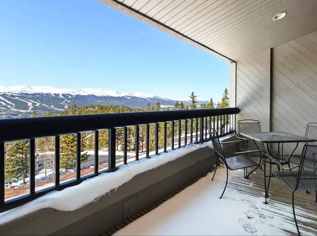 A balcony with a metal railing, a table, and chairs.
