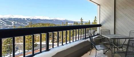 A balcony with a metal railing, a table, and chairs.