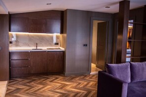 A modern kitchen with wooden cabinets, a marble countertop, and a herringbone-patterned floor. - Istanbul Park Hotel (Tuzla)