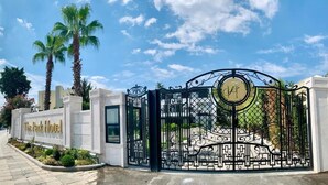 The Park Hotel entrance with a gated driveway, palm trees, and a clear sky. - Istanbul Park Hotel (Tuzla)