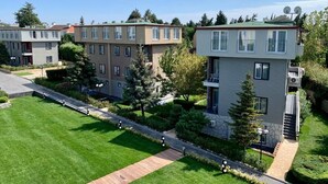 A residential complex with modern apartment buildings, a well-maintained lawn, and a clear sky. - Istanbul Park Hotel (Tuzla)