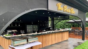 An outdoor bar area with a wooden counter, a white table, and a sign that reads "The Patio Bar". - Istanbul Park Hotel (Tuzla)