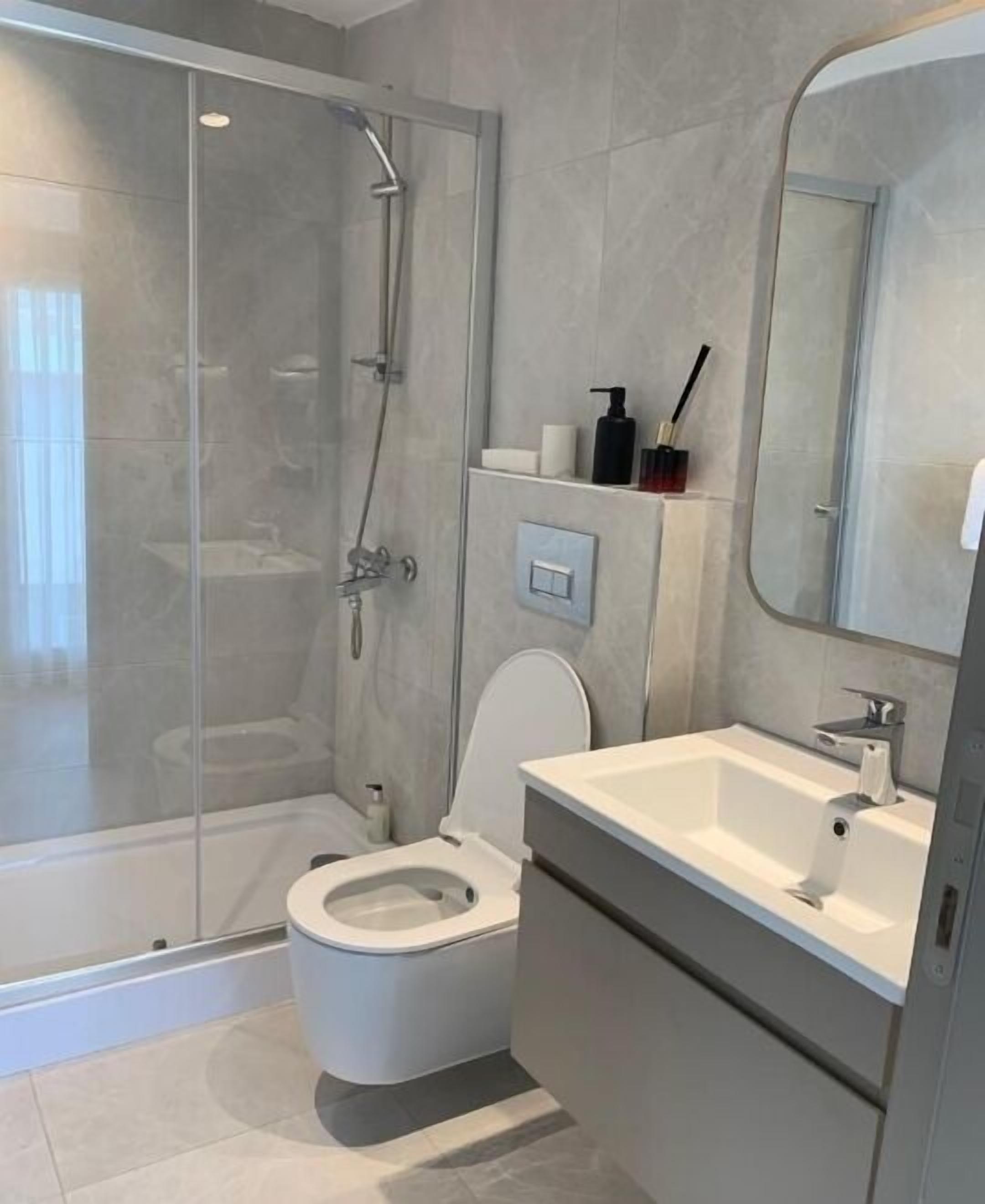 Ein modernes Badezimmer mit Duschkabine, Toilette und Waschbecken mit Spiegel.