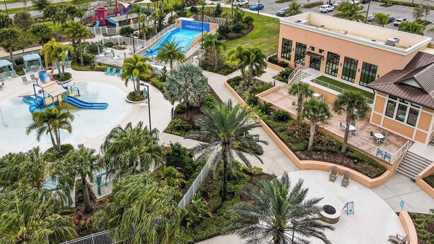Eine Luftaufnahme eines Resorts mit Schwimmbad, Wasserrutschen, Palmen und einem Gebäude mit Balkon.