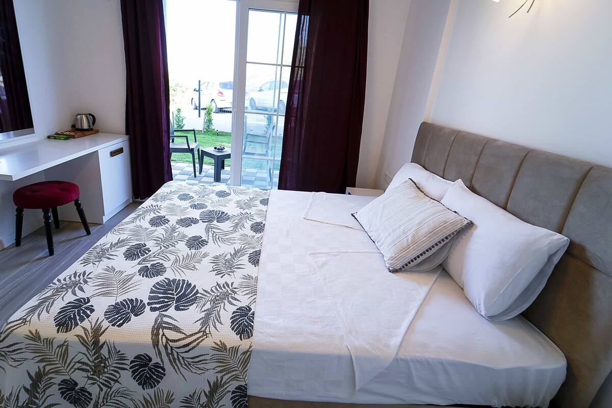 A hotel room with a bed, a desk, a chair, and a view of the outdoors.