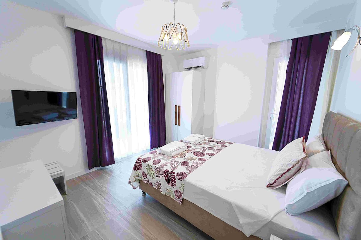 A modern bedroom with a bed, a TV mounted on the wall, and a desk.