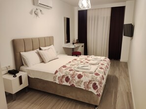 Una habitación de hotel con cama, mesita de noche y escritorio con silla.