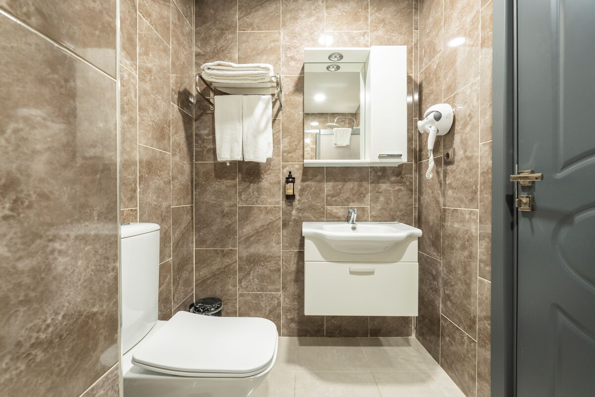 Een badkamer met toilet, wastafel, handdoekhouder en spiegel.