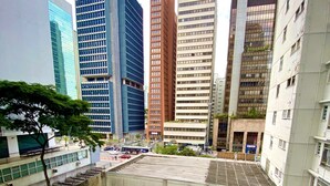 A modern urban building with a rooftop garden and surrounding high-rise structures.